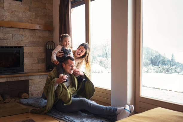 Young family on winter vacation, looking through window